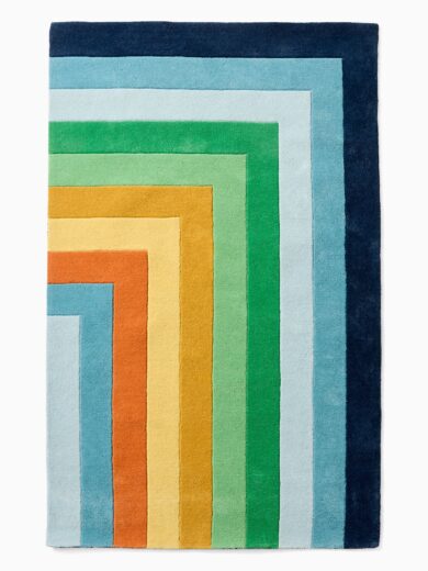 Rainbow pastel kids rug with layered corner stripe design in blue, sky blue, yellow, and orange tones, soft plush rug for nursery and playroom decor.